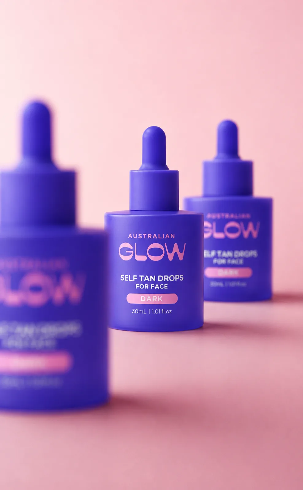 Australian Glow Self Tan Drops for Face, three purple dropper bottles on pink