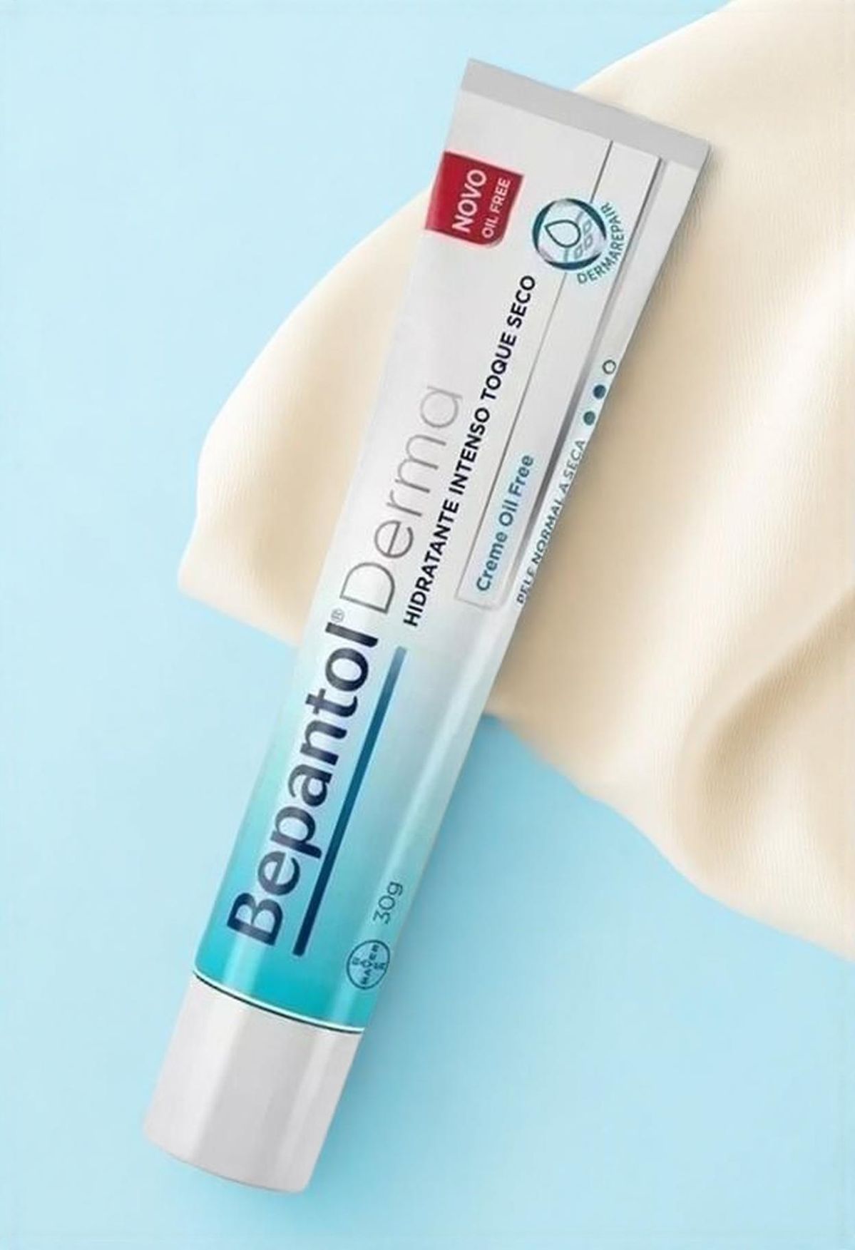Bepantol Derma tube on cobalt blue with cream silk drape, clinical studio still