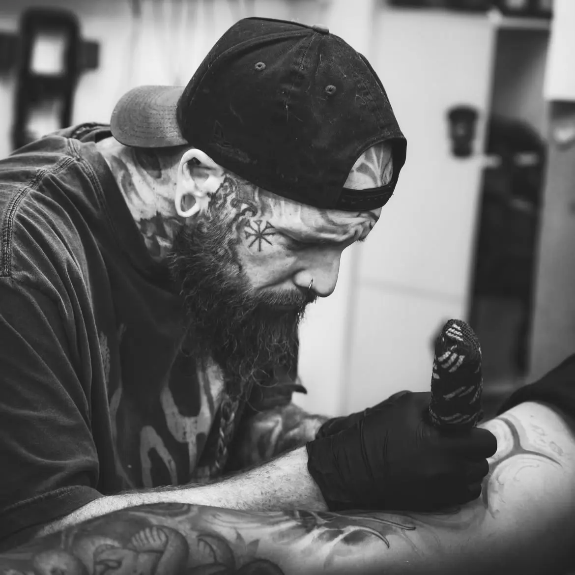 Artist mid-session, gloved hands and machine