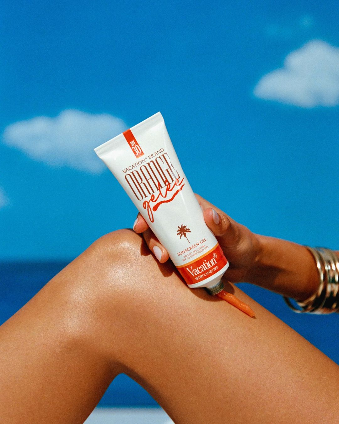 Vacation Orange Gelee SPF 30 in hand against blue sky