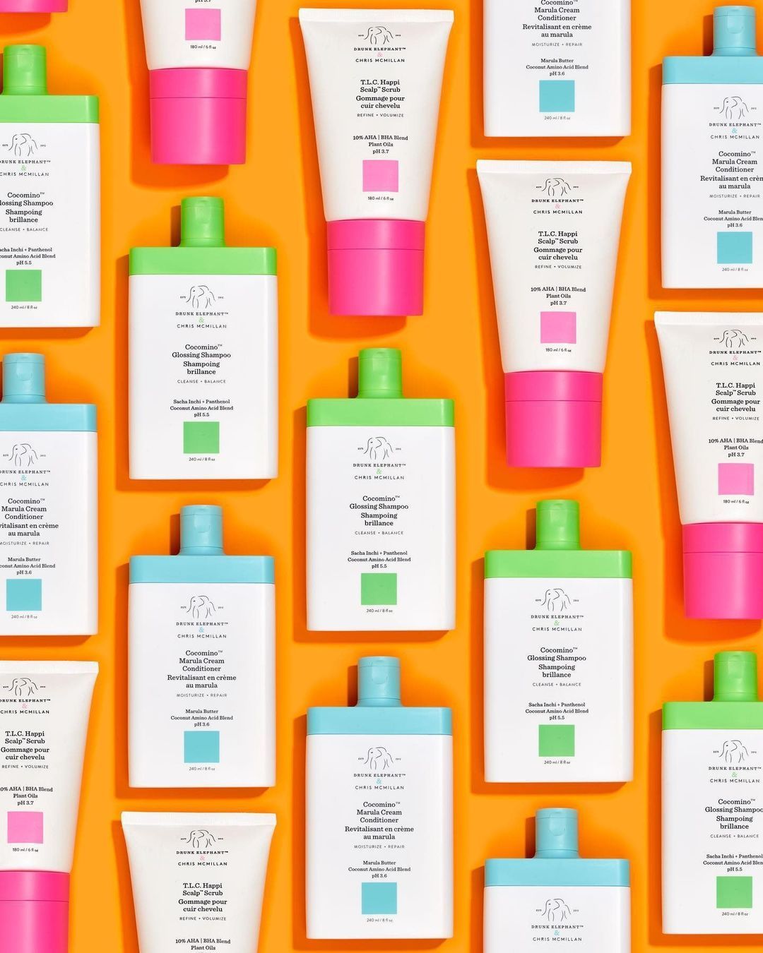 Drunk Elephant x Chris McMillan Cocomino Glossing Shampoo and Marula Cream Conditioner repeating on orange, haircare campaign flatlay