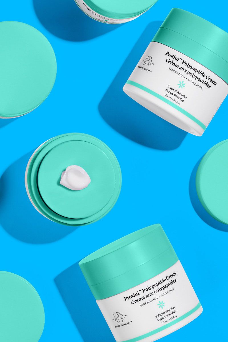 Drunk Elephant F-Balm Electrolyte Waterfacial in turquoise, bottle on blue paper cut shapes