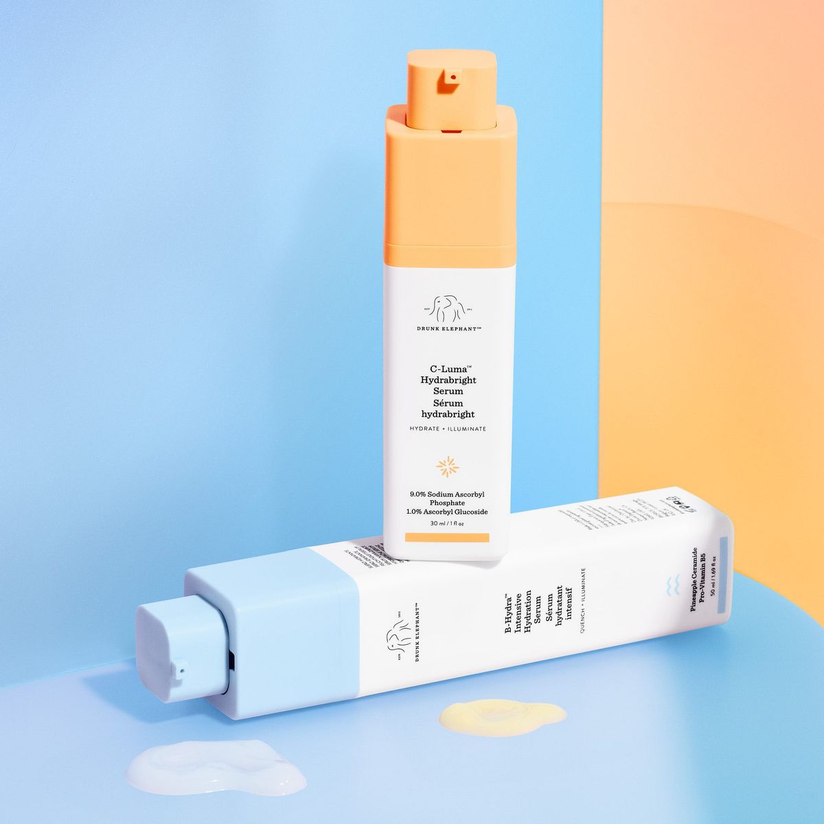 Drunk Elephant C-Luma Hydrabright Serum and B-Hydra Intensive Hydration Serum, orange and pale-blue bottles on pastel set