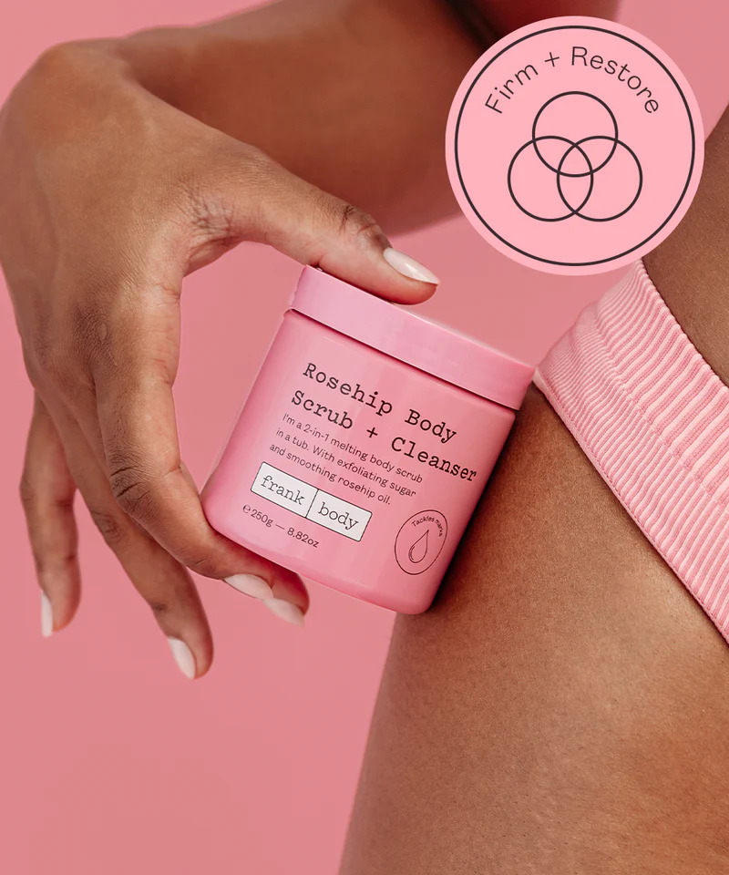 Frank Body Rosehip Body Scrub and Cleanser held against a model's leg