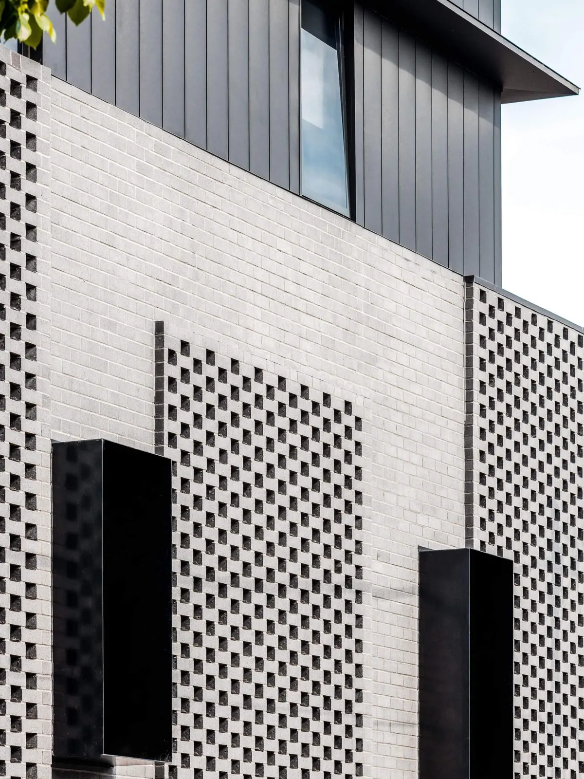The building, metal-clad top floor above the brick screen