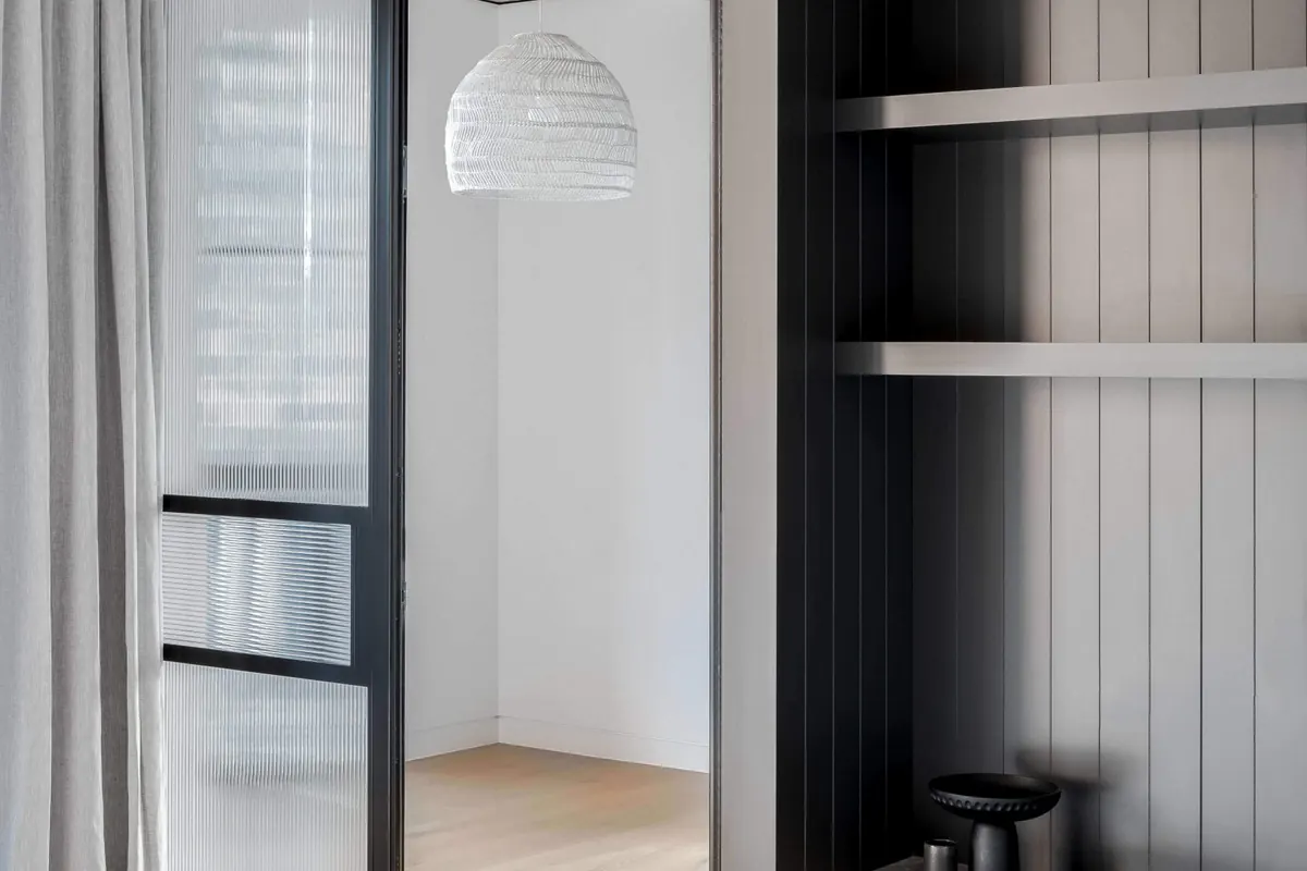 Living area with black steel-framed glass partitions and built-in joinery